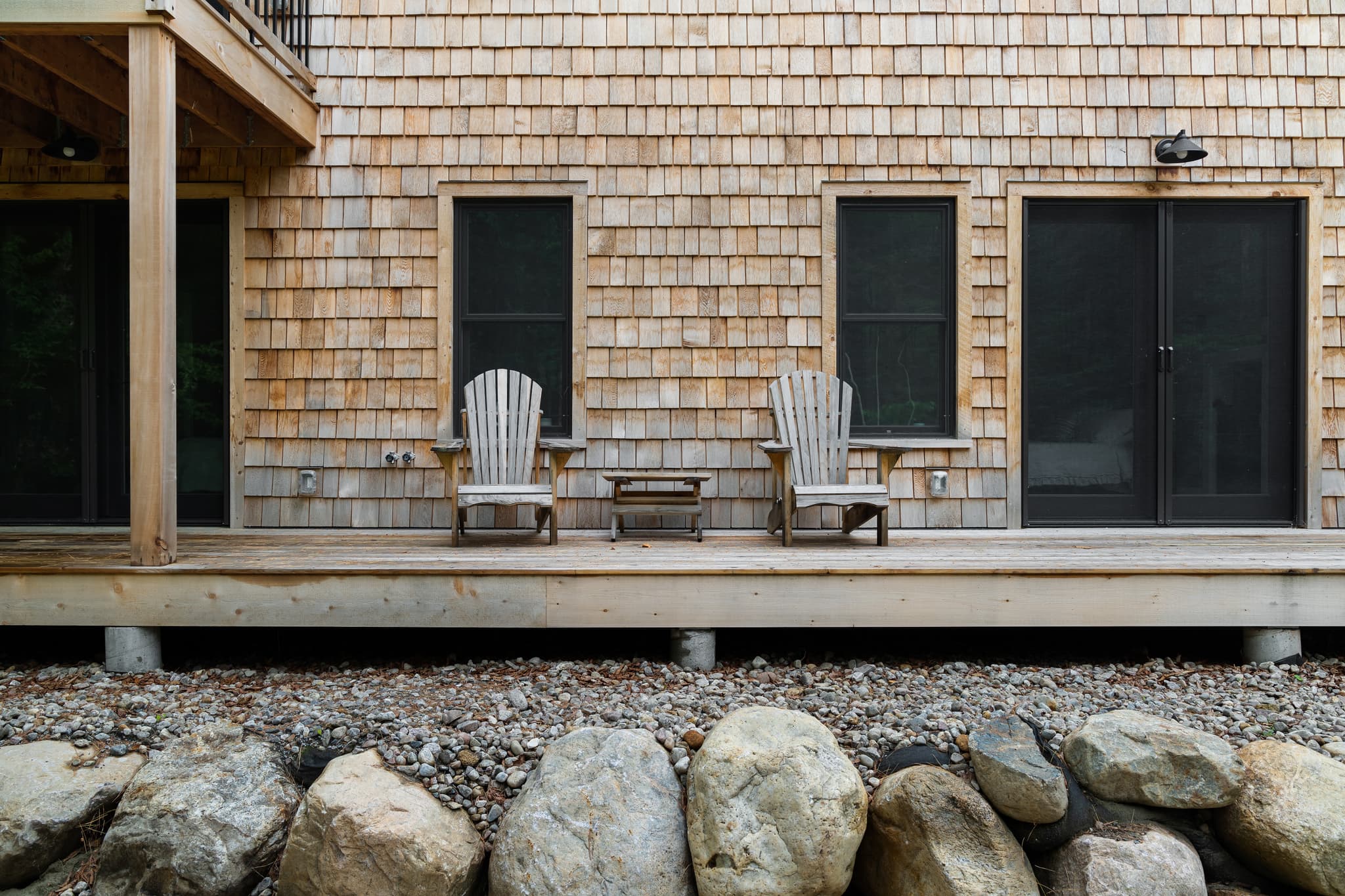 Two wooden chairs overlooking a deck, surrounded by wood siding.